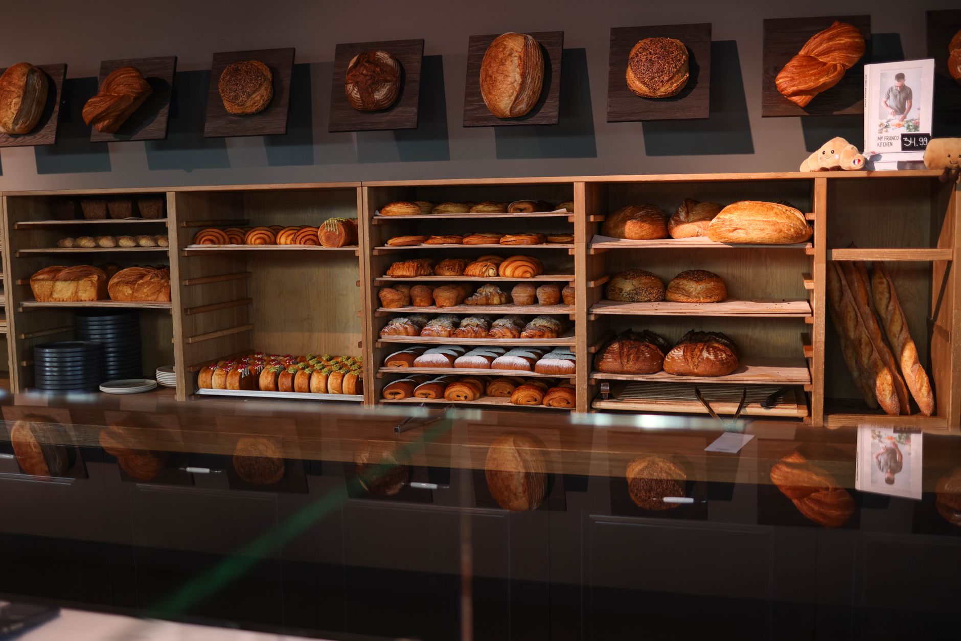 Freshly baked bread and pastries lined up on wooden shelves in a cosy bakery